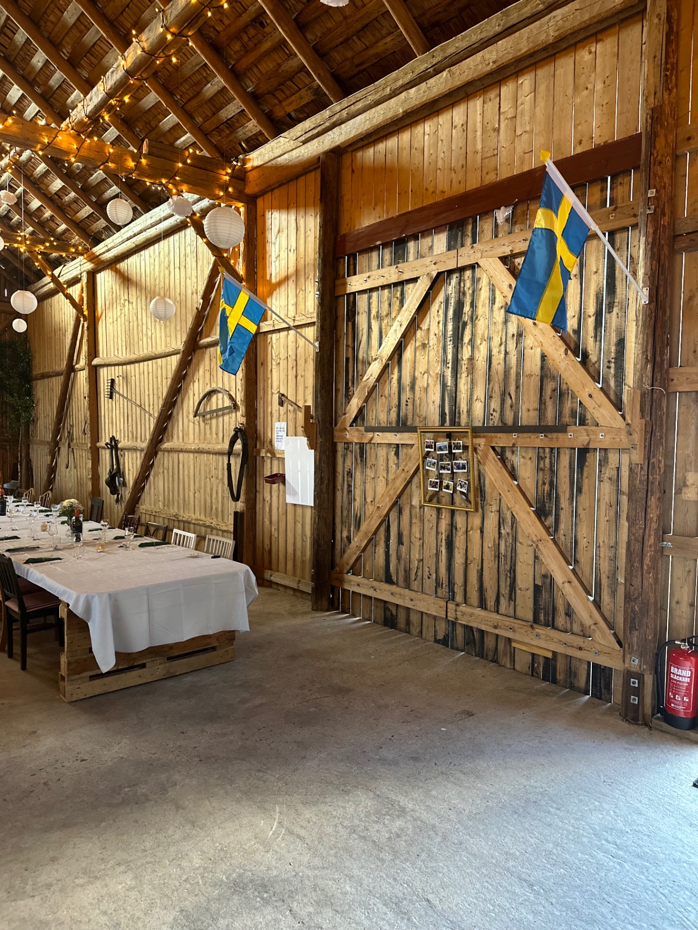 Festlokalens insida med långbord, ljusslingor och svenska flaggor